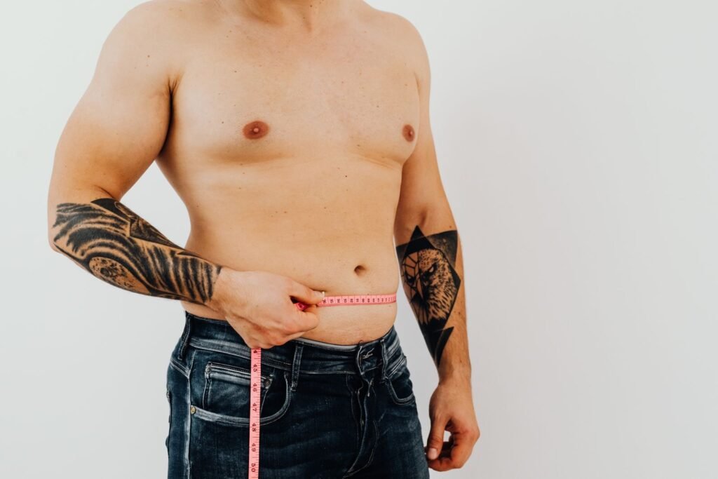 Man measuring his waist with a tape measure, illustrating the FUPA in men guide