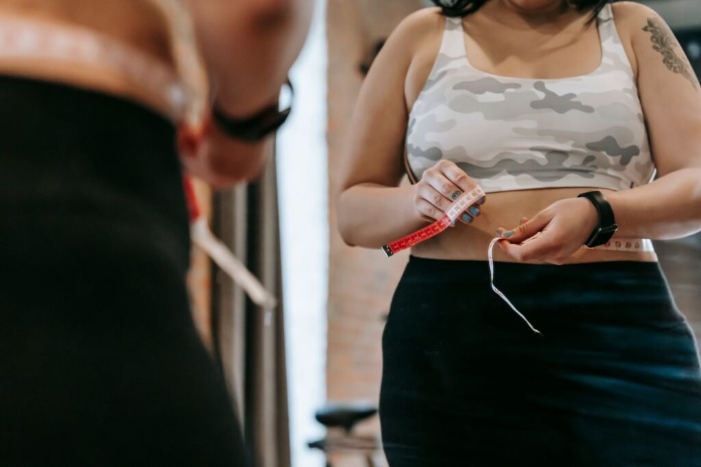 Woman measuring her waist, illustrating the difference between a FUPA and a gunt